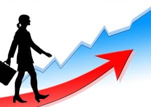 illustratiom of a women walking on a red arrow that arcs up and set in front of line chart that is also going up